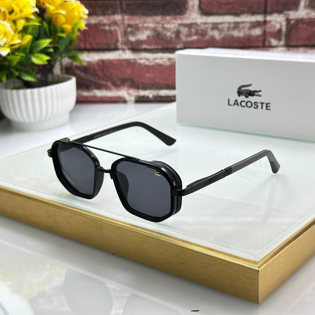 Black sunglasses on a reflective surface with Lacoste packaging in the background