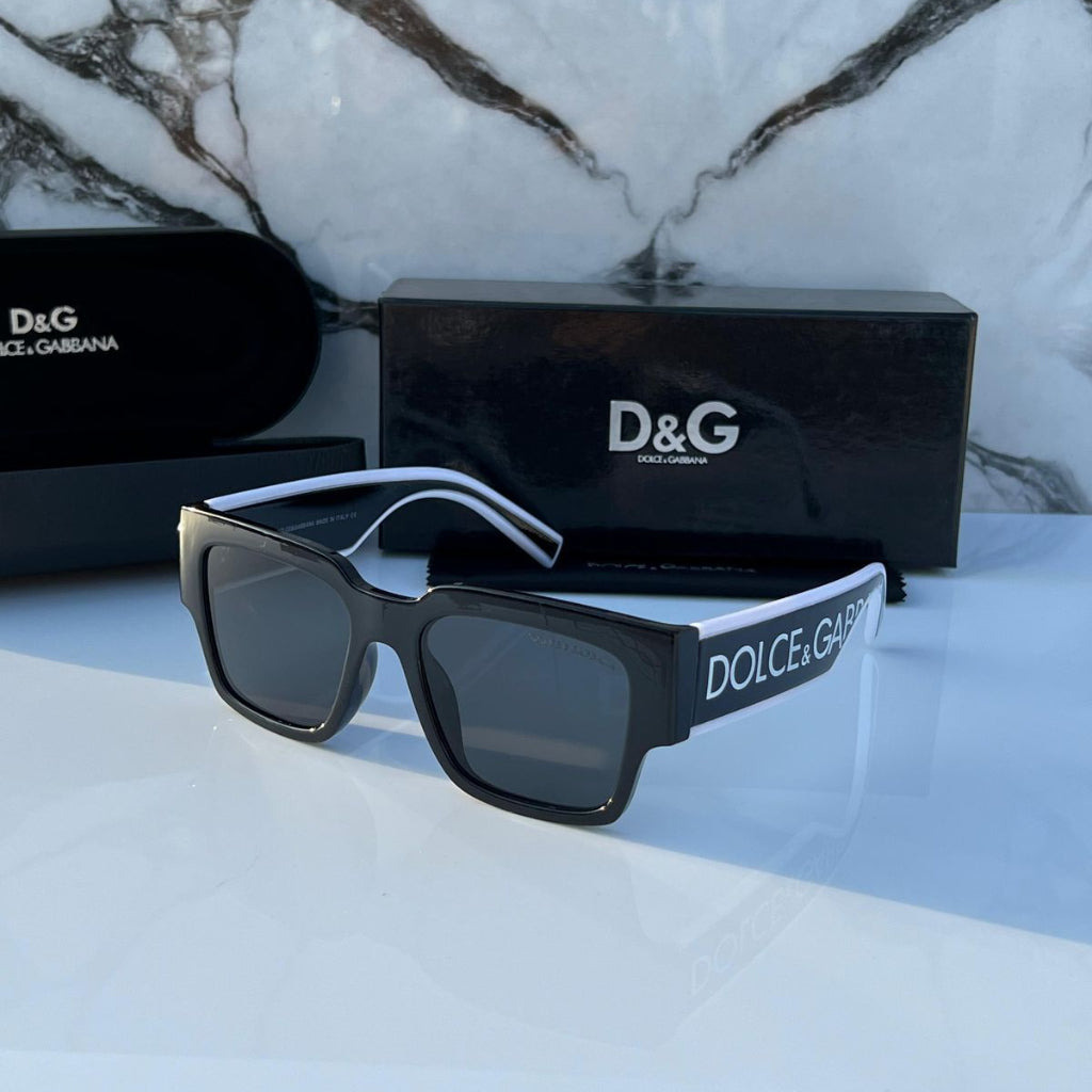 Dolce & Gabbana sunglasses with black frame and dark lenses on a marble surface.