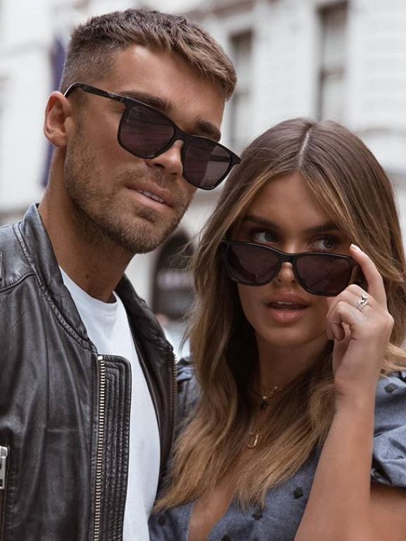 Man and woman wearing sunglasses with a blurred urban background