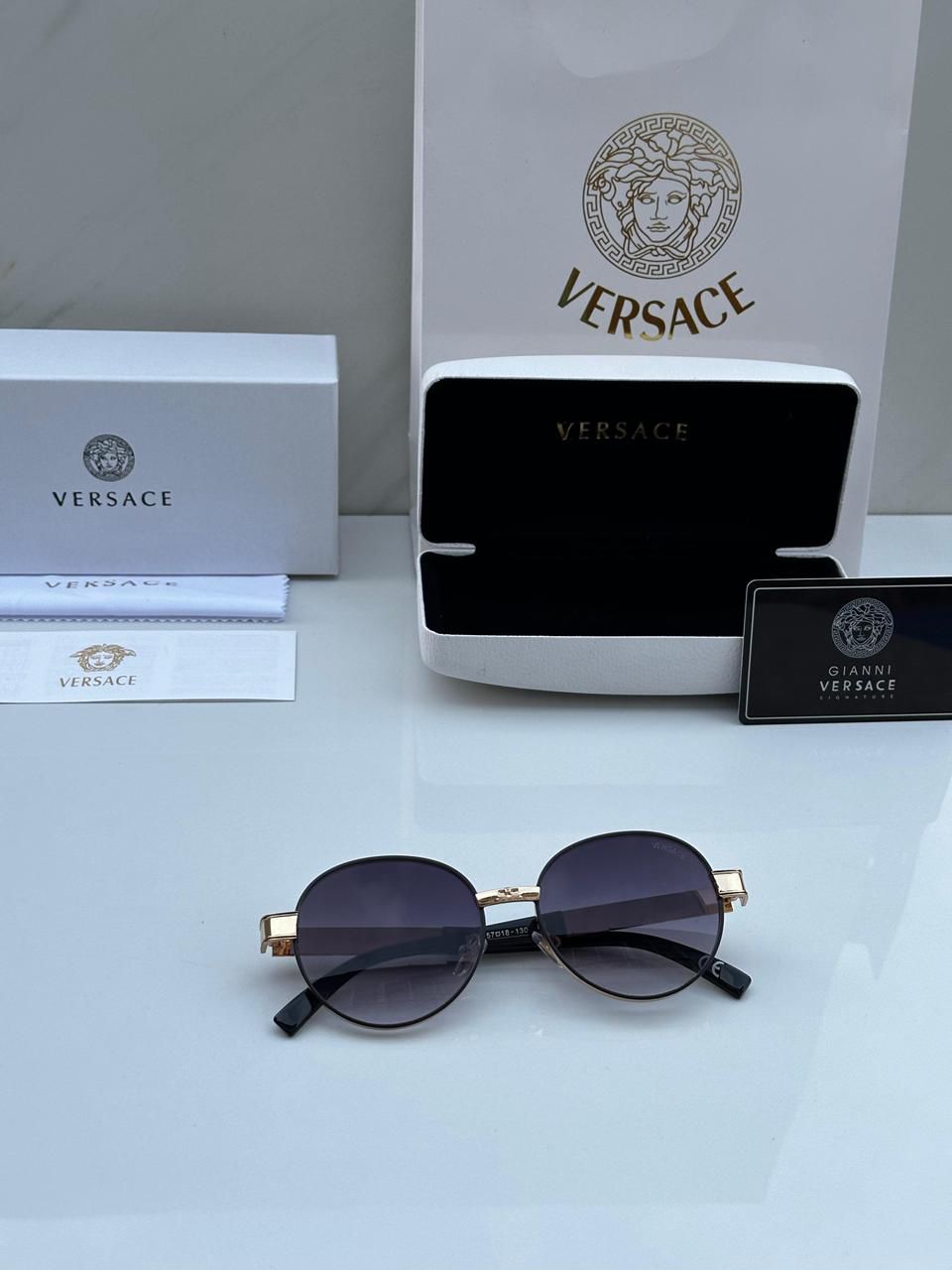 Versace sunglasses with packaging and logo on a light gray background